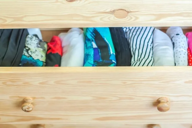 A close-up shot of several essential wardrobe items neatly arranged on a wooden surface. The items include a crisp white dress shirt, a navy blue blazer, a pair of dark wash jeans, leather dress shoes, and a classic watch. The arrangement emphasizes quality and style.