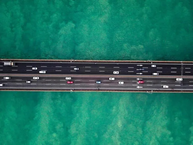 An aerial shot of a modern, well-maintained highway interchange with cars flowing smoothly, illustrating efficient infrastructure and economic movement. The image should convey progression and connectivity.