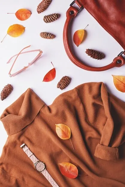 A flat lay of classic accessories, including a beige trench coat, a high-quality leather tote bag, minimalist gold jewelry, and a silk scarf, arranged neatly on a light-colored surface.