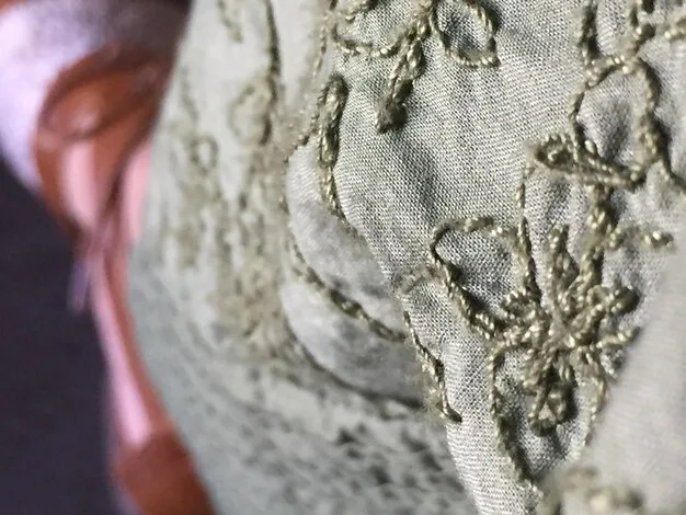 A close-up shot of an embroidered silk detail on a 1930s evening gown, highlighting the intricate craftsmanship.