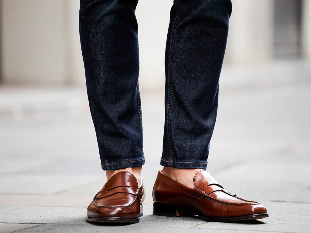 Well-tailored dark wash jeans paired with sophisticated loafers, highlighting smart casual footwear and denim.