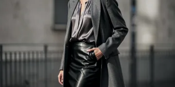 Woman in elegant monochrome outfit mixing wool, silk, and leather textures.