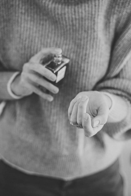 A close-up shot of a person's wrist, gently applying a fragrance from a sleek, minimalist bottle, with the background slightly blurred to emphasize the act of application and the texture of the skin.]