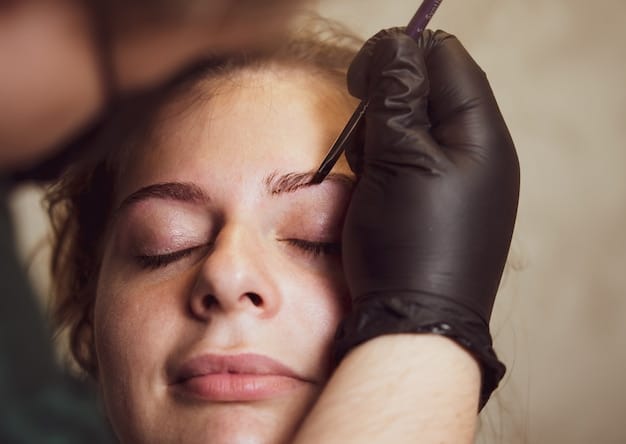 A woman receiving a nano brow treatment. The technician is using a precise tool to create fine hair strokes, enhancing the woman's natural brow shape.