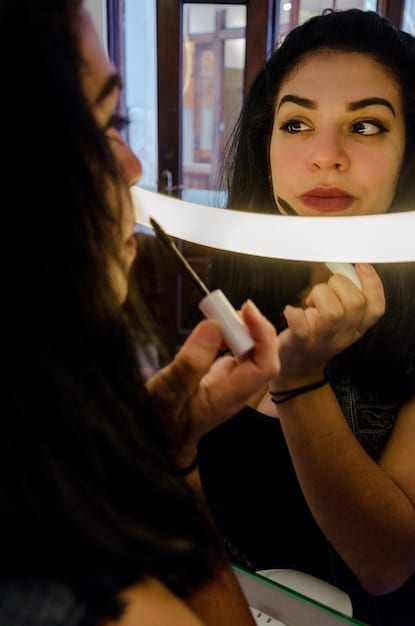 A makeup artist applying highlighter to a model's cheekbone, demonstrating the technique for achieving a dewy, highlighted effect. The focus is on the application and the resulting glow.