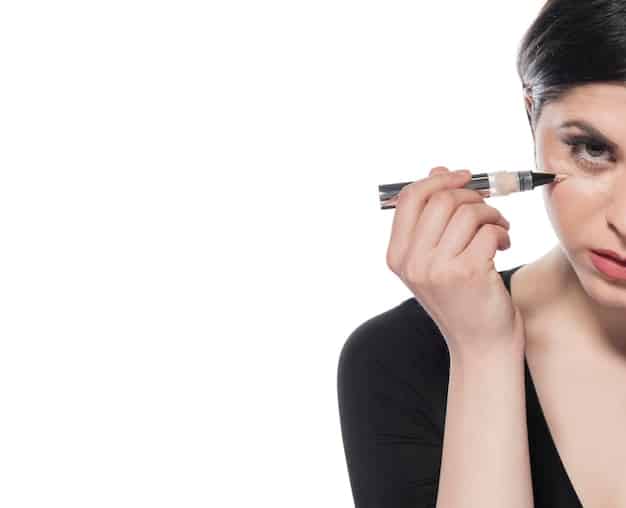 A woman carefully trimming false eyelashes with small scissors, focusing on the outer corner to ensure a perfect fit for her eye.