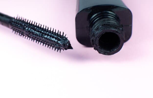 A close-up of a tube of mascara with a dried-out brush and flakes around the opening. The mascara appears clumpy and unusable, clearly indicating it has expired.