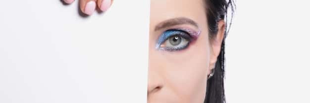 A split image showing one eye with perfectly applied false eyelashes and the other eye without any makeup, highlighting the dramatic difference in appearance. The background is a soft, blurred studio setting.