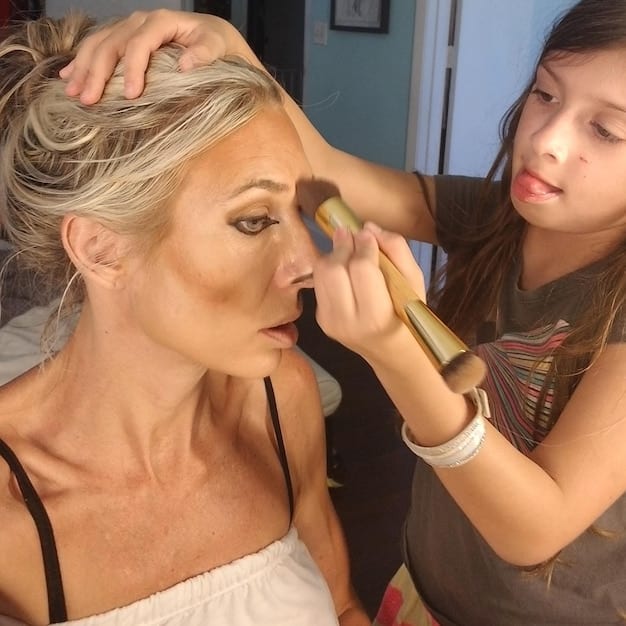 A makeup artist demonstrating the contouring technique on a model's cheekbone using a contour brush and powder. The focus is on the placement and blending of the contour.