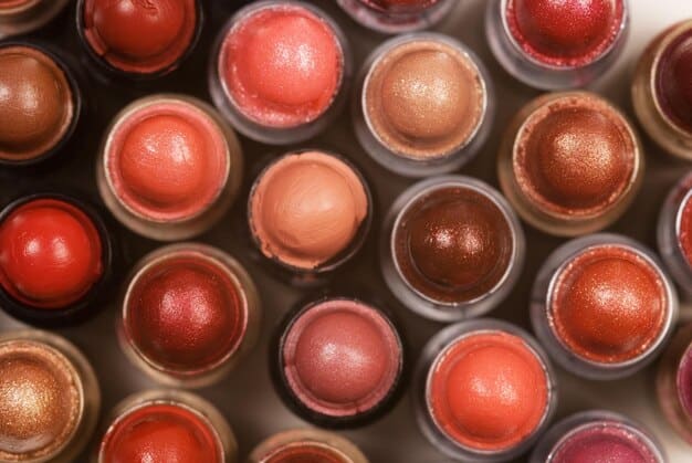 A close-up of various lipstick shades in warm tones, including nude, peach, terracotta, berry, and warm red. The lipsticks are arranged on a neutral background, highlighting their rich and inviting colors, perfect for fall.
