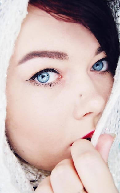 A close-up shot of a woman's eyes, showcasing the subtle enhancement of eyeliner and eyeshadow applied over her existing daytime makeup. The focus is on the precision and technique used to create a smoky effect.