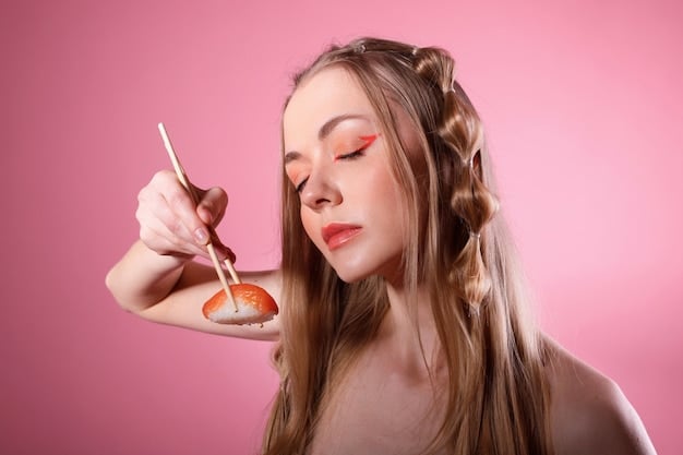 A woman applying coral blush to her cheeks with a makeup brush. The focus is on the blush and the brush, with a blurred background of a vanity and other makeup products.