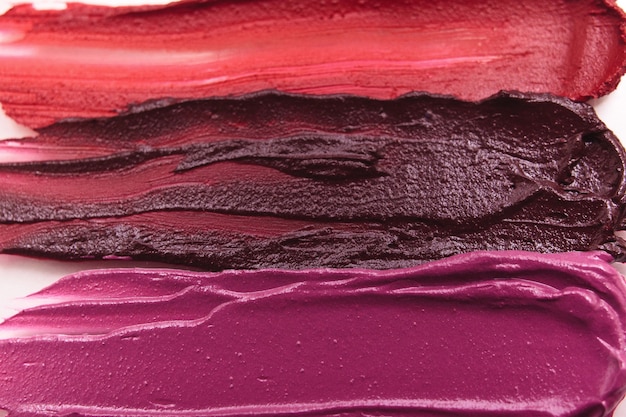 A collection of berry-toned lipsticks ranging from light pinkish-berry to deep plum. Swatches of the lipsticks are shown on a light skin tone to demonstrate the color variation.