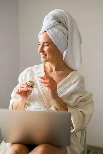 A woman applying moisturizer to her face in a well-lit bathroom. The focus is on her hands gently massaging the product into her skin, emphasizing her healthy and radiant complexion.