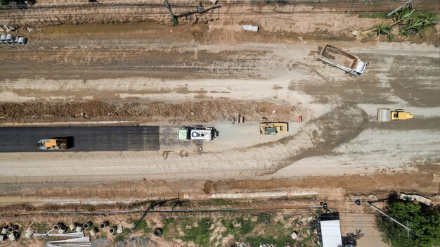 An aerial view of a construction site with heavy machinery, new road sections, and partially built bridges under construction, illustrating progress on a major infrastructure project.