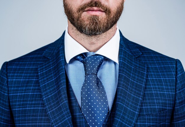 A close-up shot of a well-dressed man's torso, featuring a crisp white dress shirt, a subtly patterned silk tie, and a sharp navy blazer, highlighting the impeccable fabric and fit.