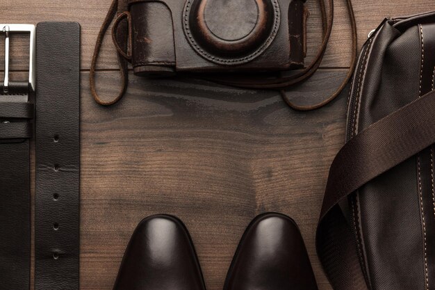 A detailed shot of various leather belts and polished leather shoes, arranged neatly on a wooden surface, showcasing different textures and shades of brown and black, emphasizing quality accessories.