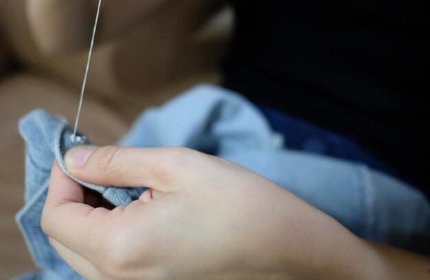 A person's hands mending a small tear in a cotton t-shirt with a needle and thread, emphasizing the importance of repairing clothes.