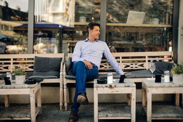 A person in a perfectly fitted button-down shirt and chinos, sitting comfortably at a cafe, showing how tailored casual wear can look effortlessly stylish. The fit is snug but not tight, with no excess fabric.
