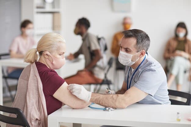 A healthcare professional, wearing scrubs and a mask, gently administering a vaccine to an adult patient's arm in a clean, modern clinic. The patient looks calm and cooperative.