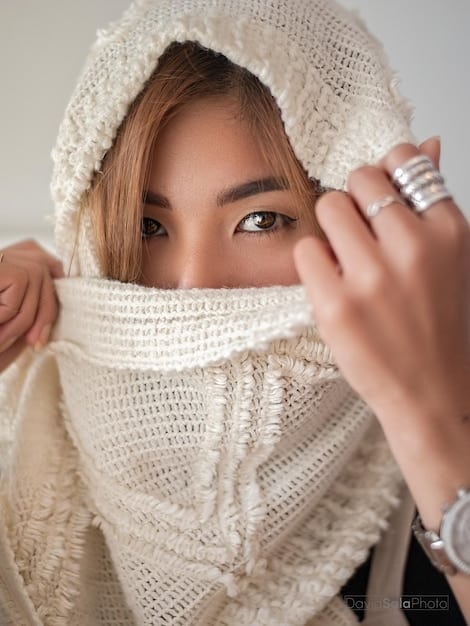 A close-up shot of a woman's hands accessorizing an outfit with a scarf and jewelry. The focus is on the details of the accessories and how they enhance the overall look, emphasizing the importance of accessorizing a capsule wardrobe for Capsule Wardrobe 2025: Build 25 Outfits with Just 10 Essential Items.
