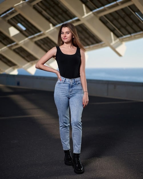 A close-up of dark wash, high-waisted bootcut jeans on a model with a pear-shaped figure. The jeans fit perfectly through the hips and thighs and flare slightly at the ankle.