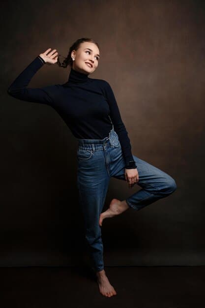 A model with an hourglass figure wearing high-rise, dark wash flare jeans and a fitted black top. The jeans accentuate her waist and create a balanced silhouette.