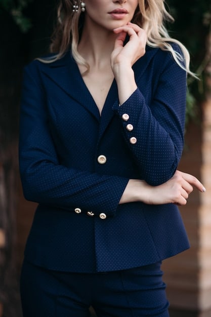 A close-up shot of a woman's outfit, showcasing a navy blazer paired with a white silk blouse and a statement necklace. The focus is on the texture of the fabrics and the elegant accessories that elevate the look. It highlights How to Style a Blazer: 5 Ways to Wear This Classic Piece with sophistication.