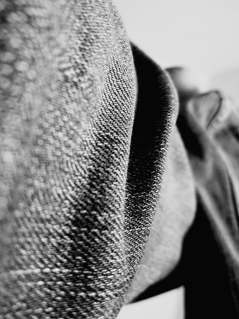 A close-up shot of different textures in a monochromatic outfit. Focus on the contrast between a smooth silk blouse, a chunky knit sweater, and textured wool pants, all in varying shades of gray. The image highlights the importance of texture in mastering monochromatic style.