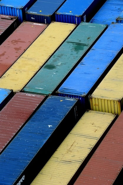 A close-up shot of shipping containers stacked high on a large cargo ship at sea. The containers are of various colors and show signs of wear, indicating their extensive journey and the complexities of global trade. The focus is on the interconnectedness of the containers and the vastness of the ocean.