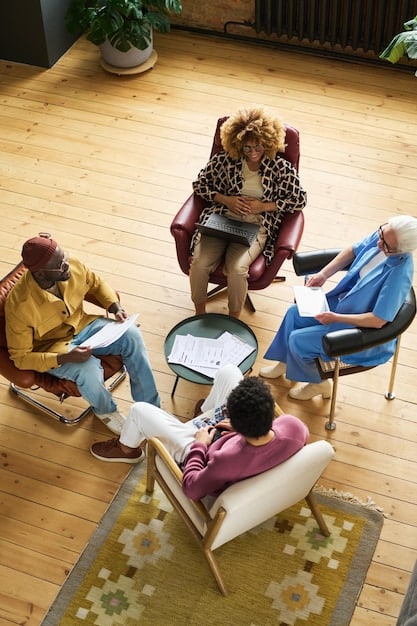 A diverse group sitting in a circle during a therapy session, with a therapist facilitating the discussion. The scene represents the importance of mental health support and counseling in overcoming addiction and understanding the opioid crisis in the US.
