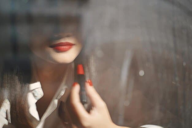 A woman's hands meticulously applying a subtle lip balm, with a blurred background of a modern, minimalist office desk, highlighting personal care in a professional context.